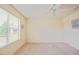 A carpeted bedroom features a large window, neutral paint and trim, and a ceiling fan at 2594 Berrington Loop, The Villages, FL 32162