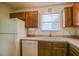 Kitchen features wood cabinets, white appliances, tile backsplash and a window over the sink at 2594 Berrington Loop, The Villages, FL 32162