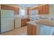 Functional kitchen equipped with white appliances, wood cabinets and tile flooring at 2594 Berrington Loop, The Villages, FL 32162