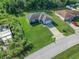 Aerial view of a well-kept home featuring a spacious lawn and quiet neighborhood street at 32 Pine Course Loop, Ocala, FL 34472