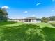 Grassy backyard view showcasing the home's exterior and screened-in lanai at 32 Pine Course Loop, Ocala, FL 34472