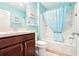 Bright bathroom featuring light blue walls, dark wooden vanity, and shower with patterned blue curtain at 3500 Countryside Path, The Villages, FL 32163