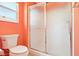 Bathroom featuring a toilet and shower with sliding glass doors and orange walls at 3500 Countryside Path, The Villages, FL 32163