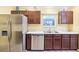 Stainless steel refrigerator and dishwasher, dark wood cabinets and tile backsplash at 3500 Countryside Path, The Villages, FL 32163