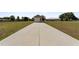 Long concrete driveway leading to a detached garage and view of the house at 4725 County Road 121D, Wildwood, FL 34785