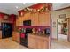 Kitchen featuring wood cabinets, black appliances and granite countertops at 4725 County Road 121D, Wildwood, FL 34785