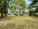Large backyard enclosed by a wooden fence, mature trees, a storage shed and partial view of the house at 6134 Se Stetson Rd, Belleview, FL 34420