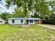 Charming single-story home with blue metal roof, white siding, and a mature tree in the front yard at 6134 Se Stetson Rd, Belleview, FL 34420