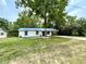 Charming single-story home with blue metal roof, white siding, and a mature tree in the front yard at 6134 Se Stetson Rd, Belleview, FL 34420