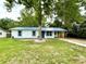 Charming single-story home with blue metal roof, white siding, and a mature tree in the front yard at 6134 Se Stetson Rd, Belleview, FL 34420