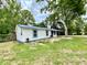 Charming single-story home with blue metal roof, white siding, and a mature tree in the front yard at 6134 Se Stetson Rd, Belleview, FL 34420