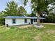 Charming single-story home with blue metal roof, white siding, and a mature tree in the front yard at 6134 Se Stetson Rd, Belleview, FL 34420