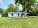 Charming single-story home with blue metal roof, white siding, and a mature tree in the front yard at 6134 Se Stetson Rd, Belleview, FL 34420