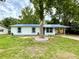 Charming single-story home with blue metal roof, white siding, and a mature tree in the front yard at 6134 Se Stetson Rd, Belleview, FL 34420
