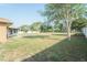Large backyard with mature trees, partial view of a covered patio, and a white perimeter fence at 7475 Se 105Th Pl, Belleview, FL 34420