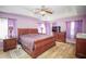 This main bedroom has wood-look floors, a ceiling fan, and bright purple walls at 7475 Se 105Th Pl, Belleview, FL 34420