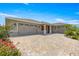 Spacious home with a three-car garage and a brick-paved driveway, enhanced by colorful flowerbeds at 8111 Sw 95Th Ct, Ocala, FL 34481