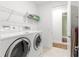 Bright laundry room featuring modern appliances, overhead shelving, and adjacent access to the hallway at 8111 Sw 95Th Ct, Ocala, FL 34481