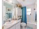 Well-lit bathroom featuring a vanity, mirror, toilet, tub, and a blue shower curtain at 8722 Sw 60Th Cir, Ocala, FL 34476