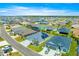 An aerial view of a residential community featuring well-maintained homes with manicured lawns under a bright blue sky at 907 Trifu Ter, The Villages, FL 32163