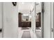 This primary bathroom is designed with double sinks, dark cabinets, tan granite counters and a decorative brown rug at 907 Trifu Ter, The Villages, FL 32163