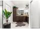 This primary bathroom is designed with double sinks, dark cabinets, tan granite counters, decor, and a brown rug at 907 Trifu Ter, The Villages, FL 32163