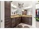 This primary bathroom is designed with double sinks, dark cabinets, tan granite counters, decor, and a large mirror at 907 Trifu Ter, The Villages, FL 32163