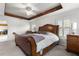 This primary bedroom offers a sleek ceiling fan, accent beams, hardwood sleigh bed, and bright natural light at 907 Trifu Ter, The Villages, FL 32163