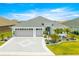 Charming single-story home featuring a well-manicured lawn, paver driveway, and a two-car garage under a bright blue sky at 907 Trifu Ter, The Villages, FL 32163