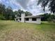 Back exterior view of a single-story home featuring a bright, green lawn at 9850 Sw 191St Ave, Dunnellon, FL 34432