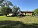Landscaped front yard of single story home featuring mature trees and stone facade at 9850 Sw 191St Ave, Dunnellon, FL 34432