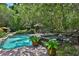 Secluded backyard pool area with a gazebo, landscaping, and a rock waterfall feature at 1300 Sw 43Rd Pl, Ocala, FL 34471