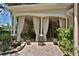 Inviting covered patio with brick flooring, columns, neutral privacy curtains, and lovely landscaping at 1300 Sw 43Rd Pl, Ocala, FL 34471
