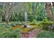Lush garden featuring a tranquil pond with a decorative fountain, surrounded by diverse foliage and mature trees at 1300 Sw 43Rd Pl, Ocala, FL 34471