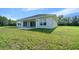 View of the home's back exterior highlighting the lawn, patio, windows and sliding glass doors at 1058 Se 59Th St, Ocala, FL 34480