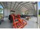 Open-sided garage showcasing a tractor, boat, and other equipment, all neatly arranged at 1058 Se 59Th St, Ocala, FL 34480