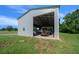 Exterior shot of a large gray garage structure with an open door, nestled in a green, grassy field at 1058 Se 59Th St, Ocala, FL 34480