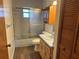 Well-lit bathroom featuring a vanity, toilet, and tub with glass doors at 10739 Se 44Th Ter, Belleview, FL 34420