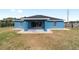 Back view of a blue single-story house with a covered patio and sliding glass doors, perfect for outdoor living at 13115 Sw 49Th Ave, Ocala, FL 34473