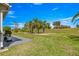 Expansive backyard featuring lush green grass, a concrete patio, and views of palm trees and the golf course at 15825 Sw 11Th Court Rd, Ocala, FL 34473