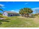 Spacious backyard with a covered patio, lush lawn, and palm trees, perfect for outdoor relaxation and entertaining at 15825 Sw 11Th Court Rd, Ocala, FL 34473