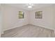 Bright bedroom with two windows, light gray wood flooring, and white walls at 2220 Ne 41St St, Ocala, FL 34479