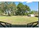 An expansive backyard with green grass, mature trees, and a storage shed for gardening tools at 3950 Se 10Th Ln, Ocala, FL 34471