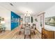 Well-lit dining room featuring a modern chandelier, glass-top table, and a vibrant blue accent wall at 514 Saint Andrews Blvd, Lady Lake, FL 32159