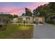 Charming single-story home featuring a well-manicured lawn, cozy porch and an American flag at sunset at 514 Saint Andrews Blvd, Lady Lake, FL 32159