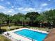 Community pool with lounge chairs and tables surrounded by mature trees and well-kept landscaping on a bright day at 519 Fairways Cir # A, Ocala, FL 34472