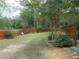 Spacious backyard with a well-maintained lawn, mature trees, and a red fence at 5949 Se 164Th Ct, Ocklawaha, FL 32179