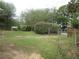 Spacious backyard showing a lawn, trees, greenery, and a small shed in the background at 5949 Se 164Th Ct, Ocklawaha, FL 32179
