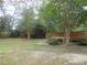 Extensive backyard with lush greenery, trees, and a seating area; bordered by a wood fence at 5949 Se 164Th Ct, Ocklawaha, FL 32179