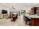 Bright living room and kitchen area with tile flooring, ceiling fan, granite countertop, and access to outdoor seating at 6394 Sw 97Th Terrace Rd, Ocala, FL 34481